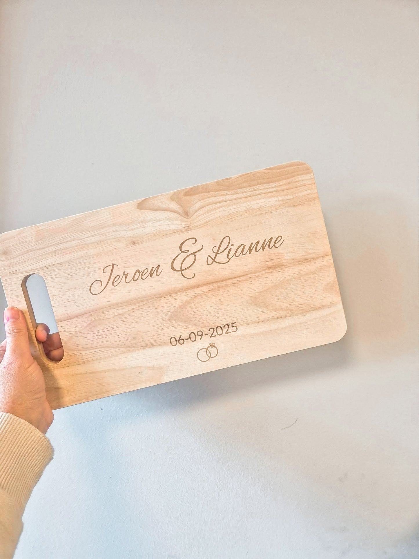 Gepersonaliseerde serveerplank met namen en trouwdatum en ringen erop.