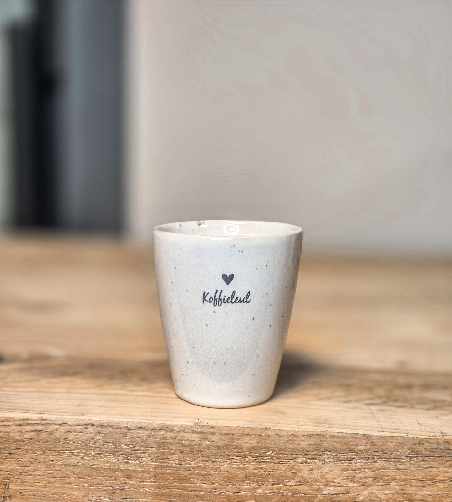 een witte mok met tekst koffieleut en een hartje