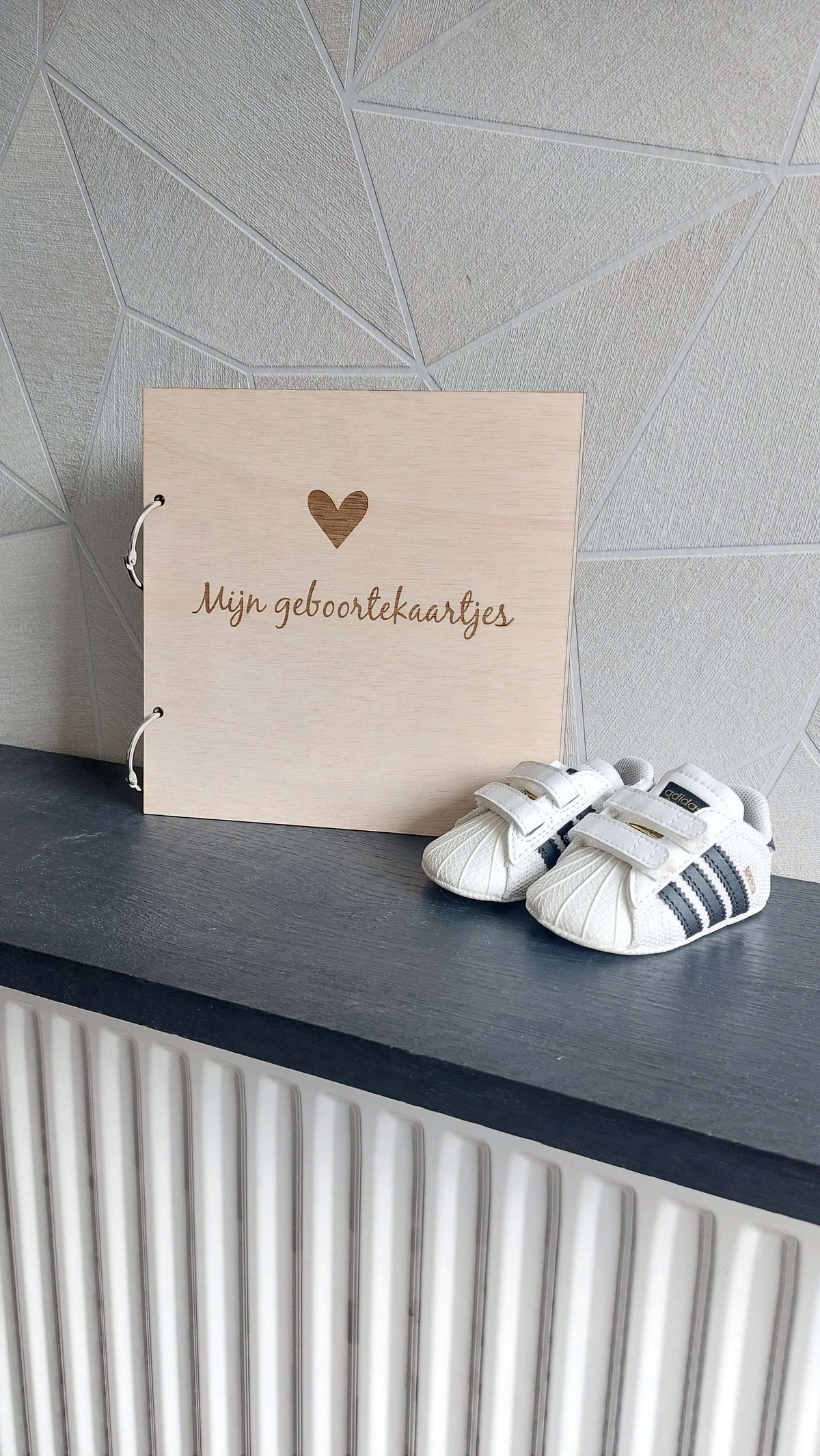 Op een plank staat een bewaarbundel voor geboortekaartjes met tekst mijn geboortekaartjes en een paar schoentjes ervoor.