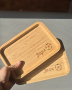 een hand die 2 broodplankjes vasthoud gepersonaliseerd met naam en een voetbal 