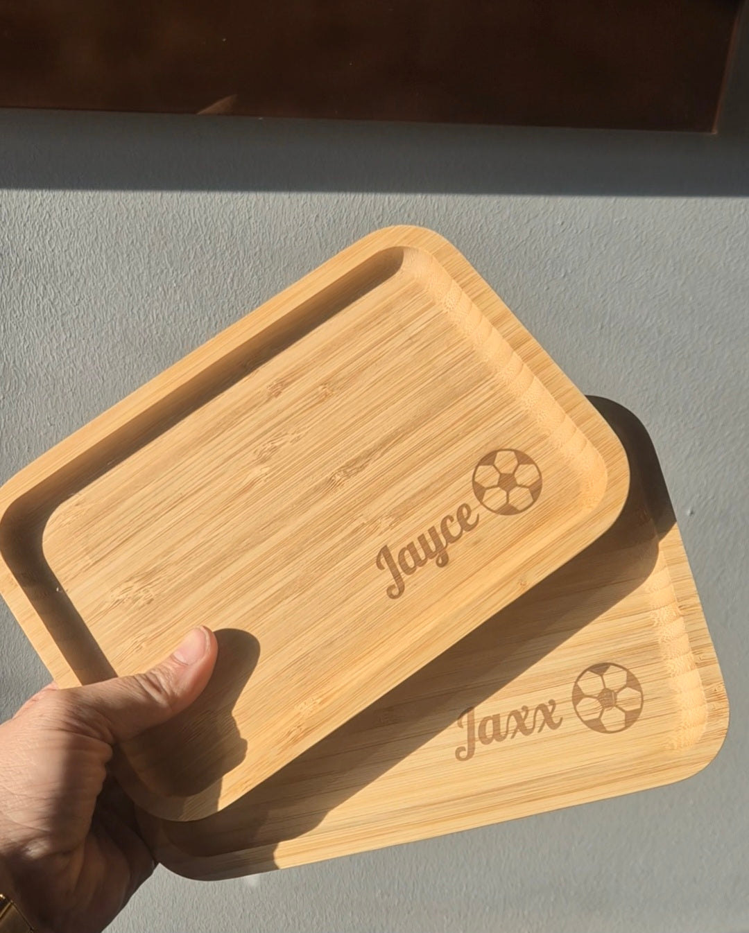 een hand die 2 broodplankjes vasthoud gepersonaliseerd met naam en een voetbal 