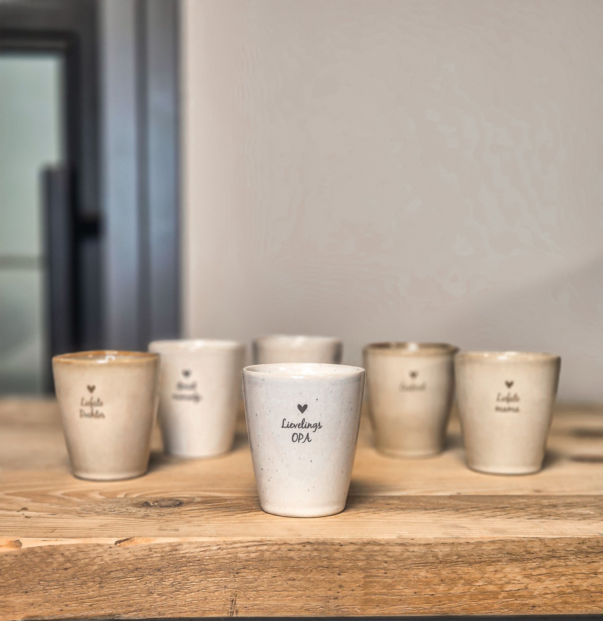 Op de voorgrond zie je een mokje met de tekst lievelings opa. Erachter staan nog meer gepersonaliseerde mokjes met andere teksten