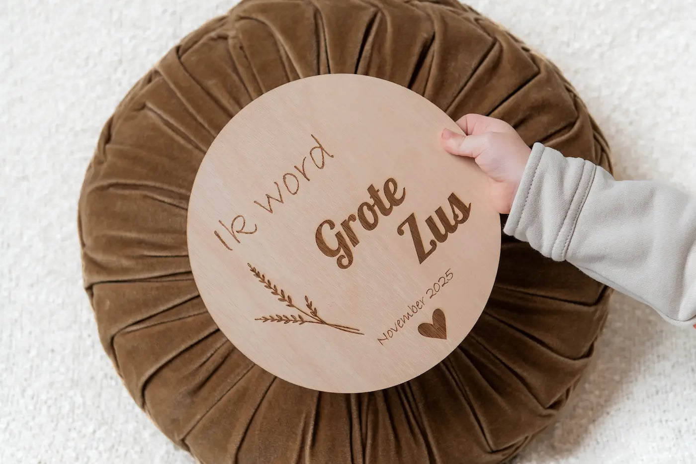 Houten zwangerschapsaankondiging cirkel met de tekst “Ik word grote zus”, gepersonaliseerd met datum, gebruikt als zwangerschapsaankondiging door een kind.