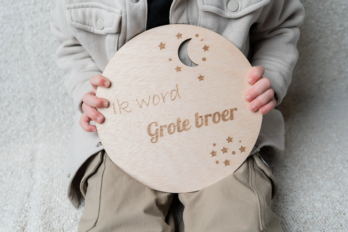 Spontane foto van kind met houten zwangerschapsaankondiging cirkel Ik word grote broer of zus als familie aankondiging