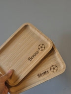 iemand houd 2 gepersonaliseerde broodplankjes vast met de namen bonnen en matts en een voetbal