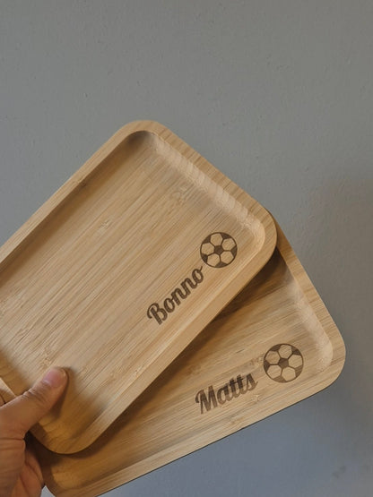 iemand houd 2 gepersonaliseerde broodplankjes vast met de namen bonnen en matts en een voetbal