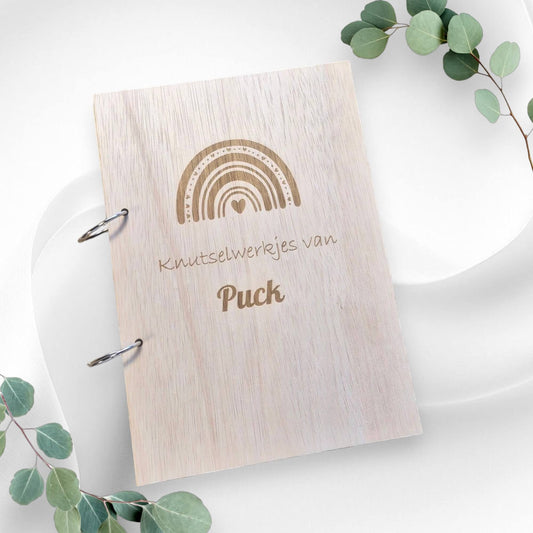 Houten A4 bewaarbundel "Knutselwerkjes van [Eigen Naam]" met regenboog en hartjes op de voorkant, ideaal voor het bewaren van de creatieve werkjes van je kindje.