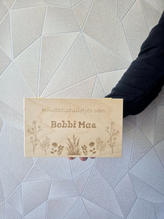 Vooraanzicht van een gepersonaliseerde houten knutselkist met naam en bloemen gravure