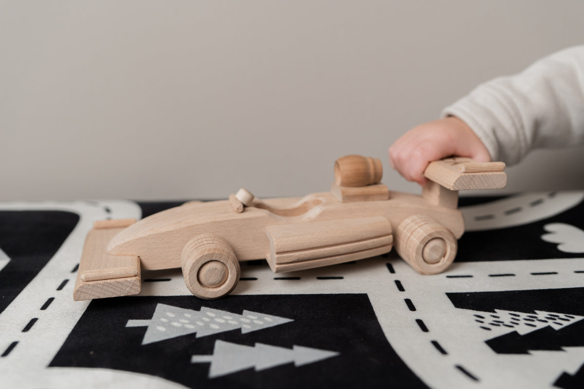 een kindje dat speelt met een houten F1 auto 