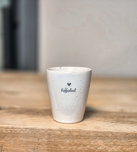 een witte mok met tekst koffieleut en een hartje