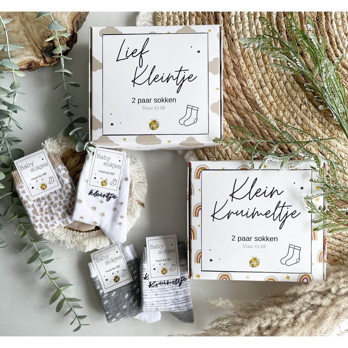 Een liefdevol ingepakte giftbox met babysokjes, met de tekst "Klein Kruimeltje", sfeervol gepresenteerd als kraamcadeau.