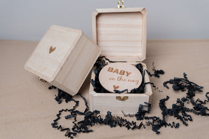 vierkant houten kistje met hartje als zwangerschapsaankondiging. er ligt een cirkel in met de tekst baby on the way